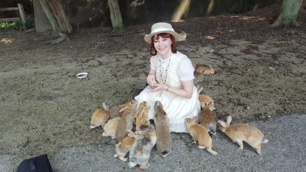 Author surrounded by rabbits on Bunny Island, Japan